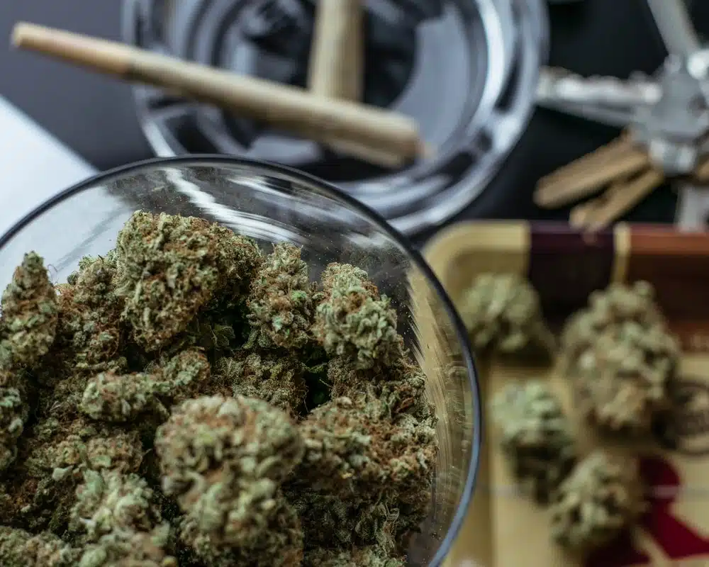 Jars of cannabis buds with some joints in the background