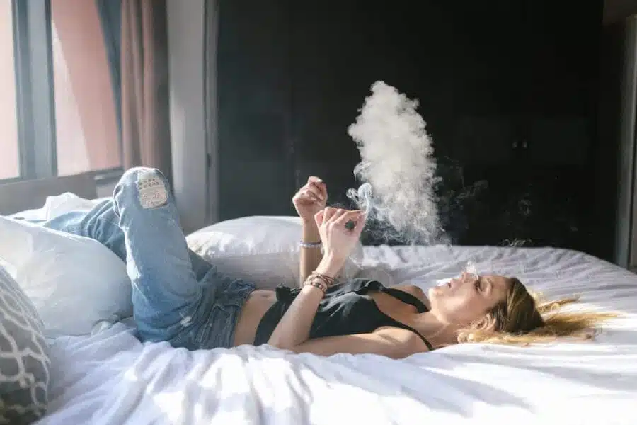 person lying in bed enjoying a joint