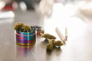 weed grinder, buds and some pre-rolled joints on a counter