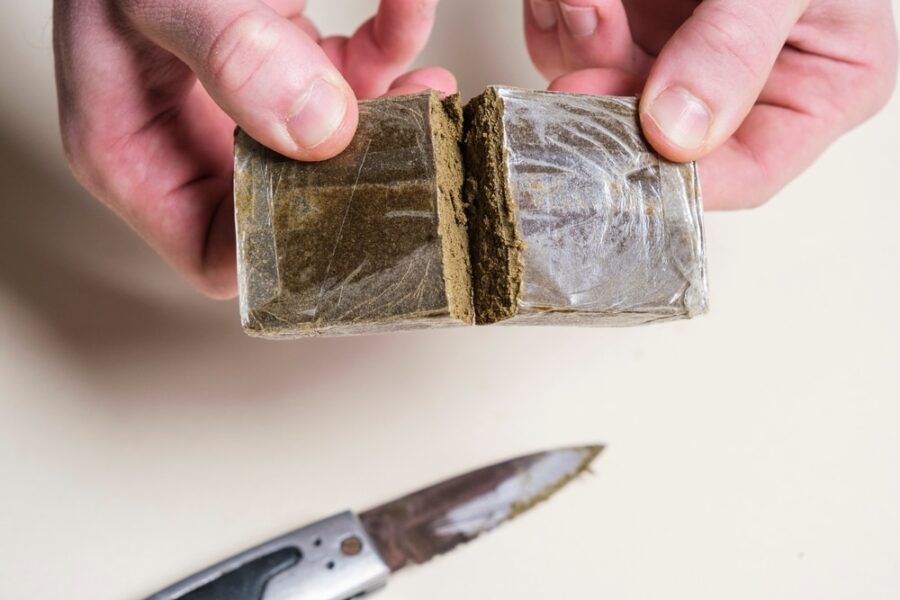 A lump of dry hash being broken into too with a knife on the table underneath