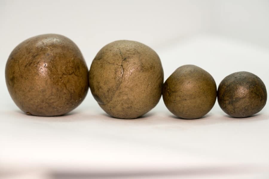 Four hand rolled hash balls of different sizes on a white surface