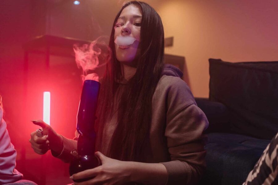 Woman exhaling weeed smoke from a homemade bong
