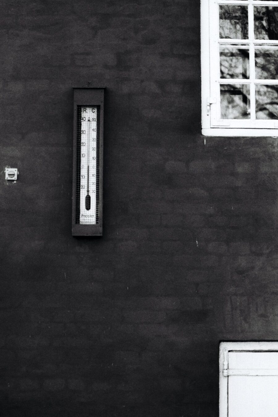 An outdoor thermometer attached to a house
