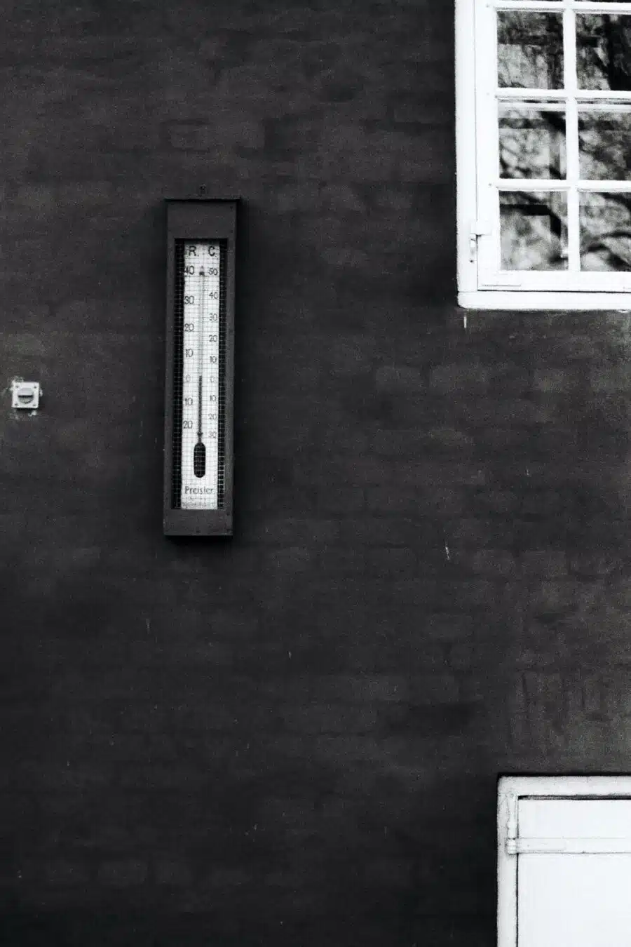 An outdoor thermometer attached to a house